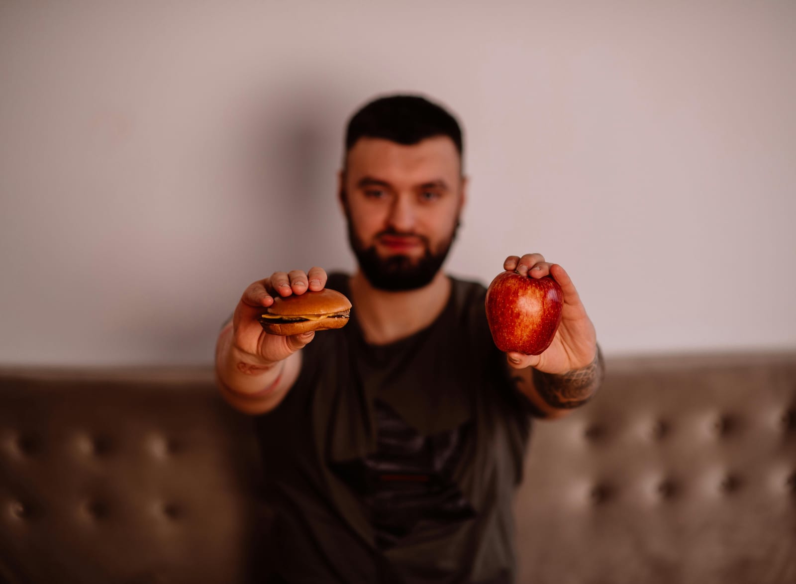 Muž drží v jedné ruce hamburger a ve druhé jablko