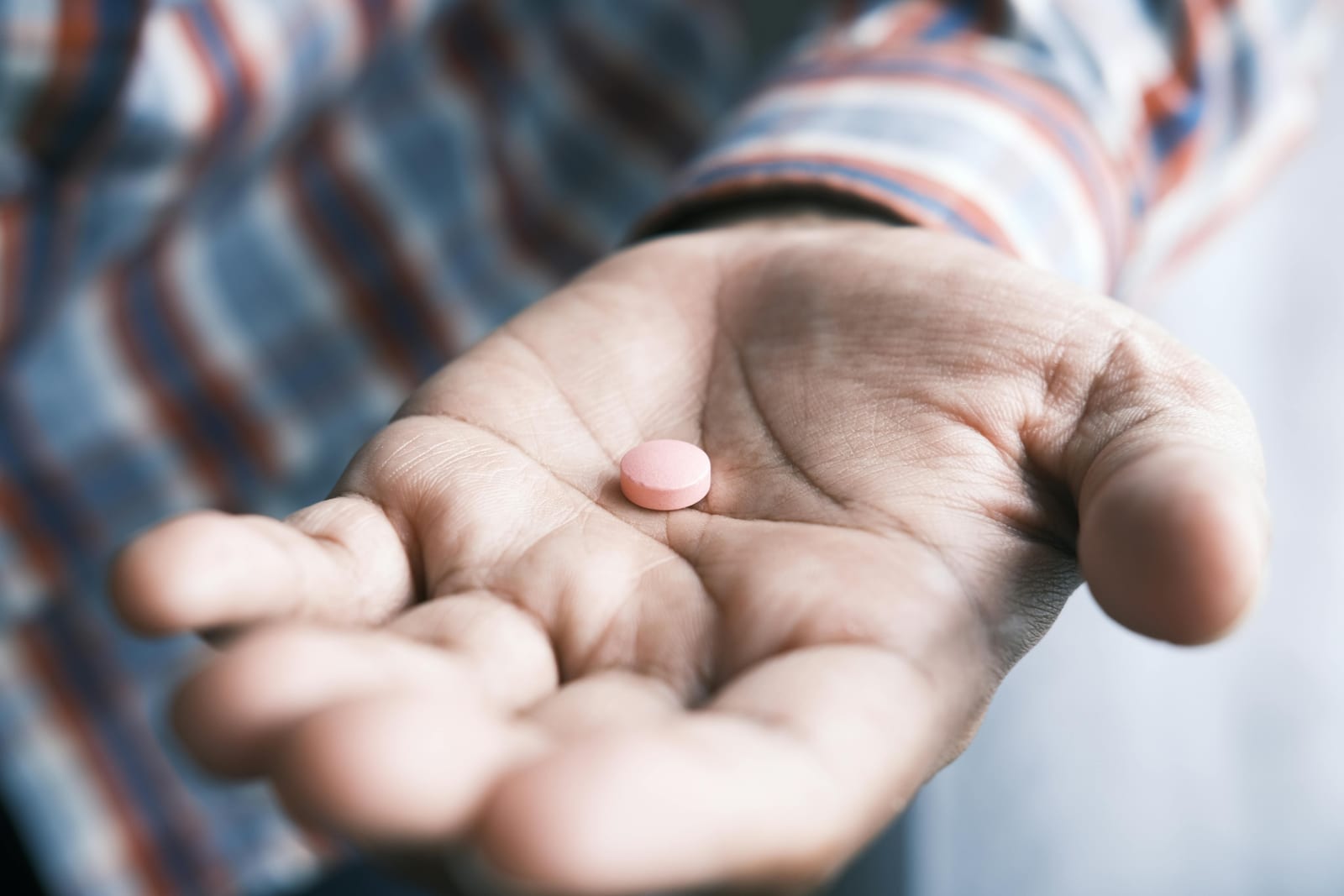 Otevřená dlaň s velkou hrstí různobarevných kapslí a tablet