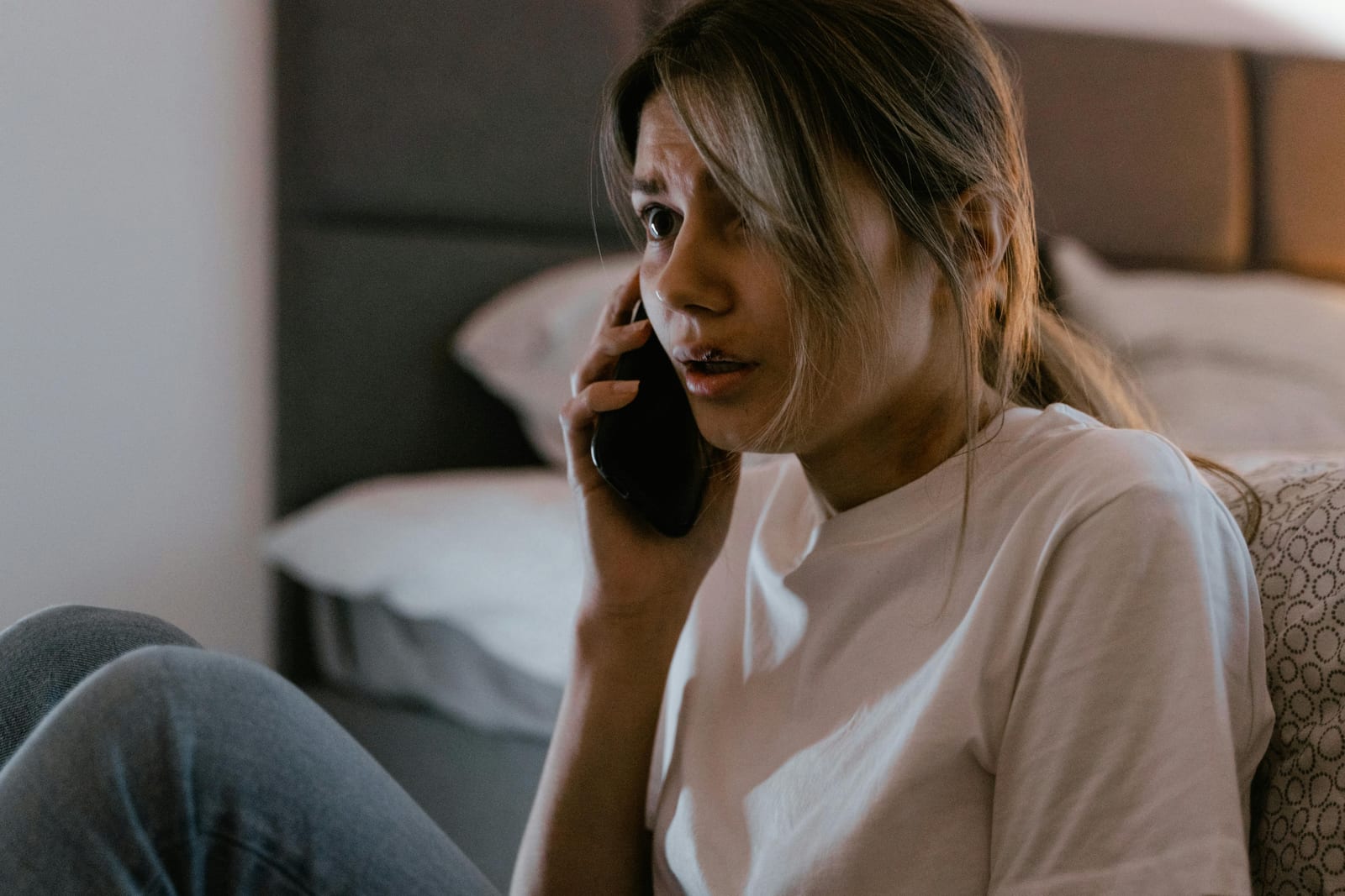 Žena s ustaraným výrazem zírá do telefonu ve tmě