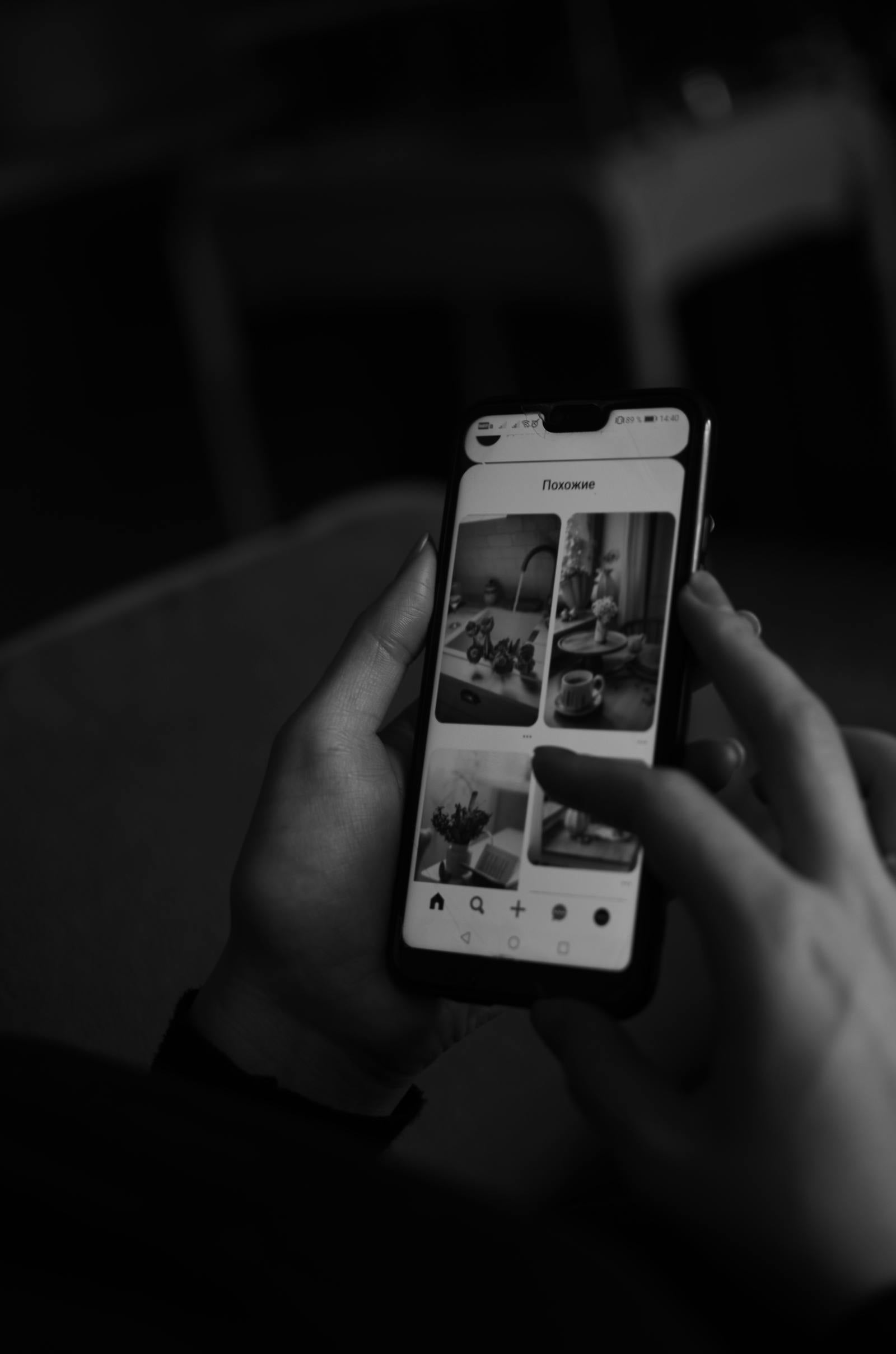 Černobílý snímek osoby listující obrazovkou telefonu