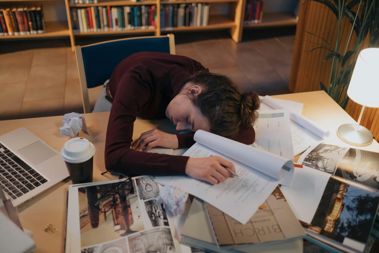 Vyčerpaný student usnul nad papíry a knihami u stolu