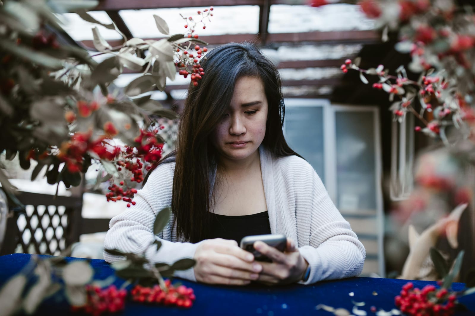 Žena sama na pohovce zamyšleně hledí do telefonu