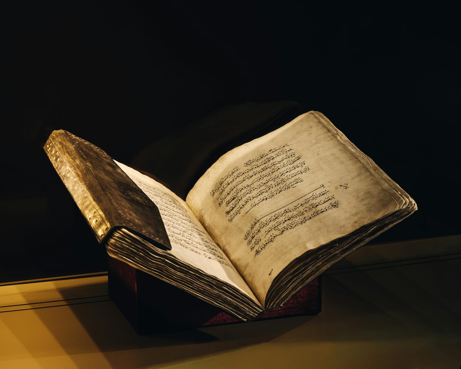 Otevřená stará bible nebo rukopis v knihovně, ztlumené osvětlení, detail stránky