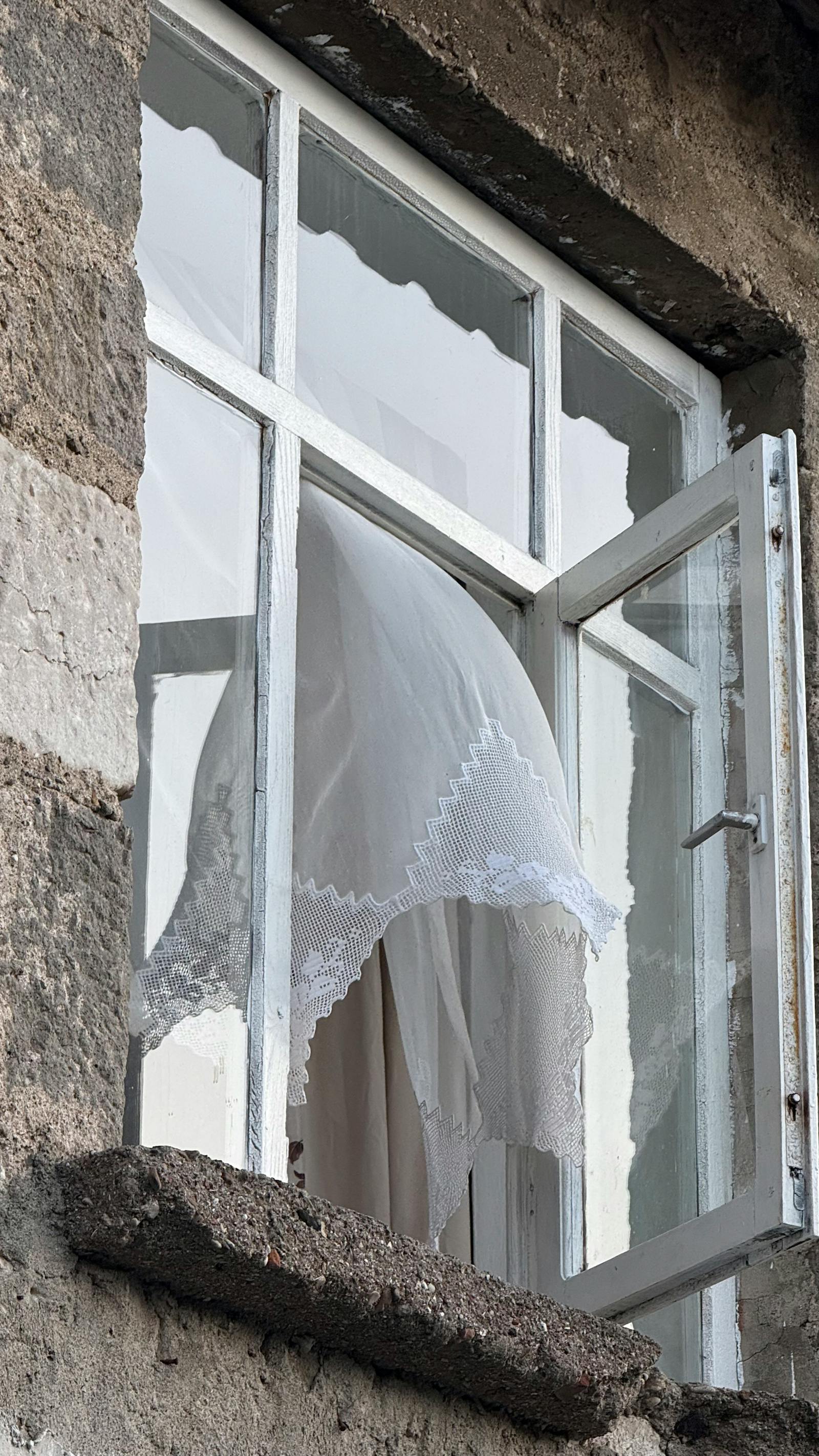 Otevřené okno s rozfoukanou záclonou