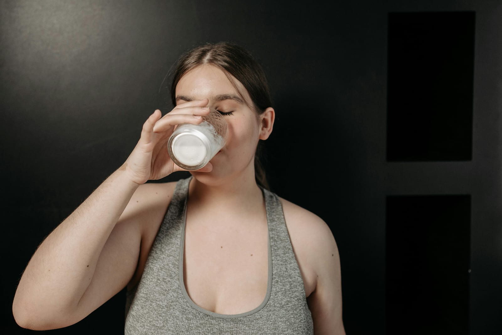 Žena pije sklenici mléka u stolu, klidná atmosféra