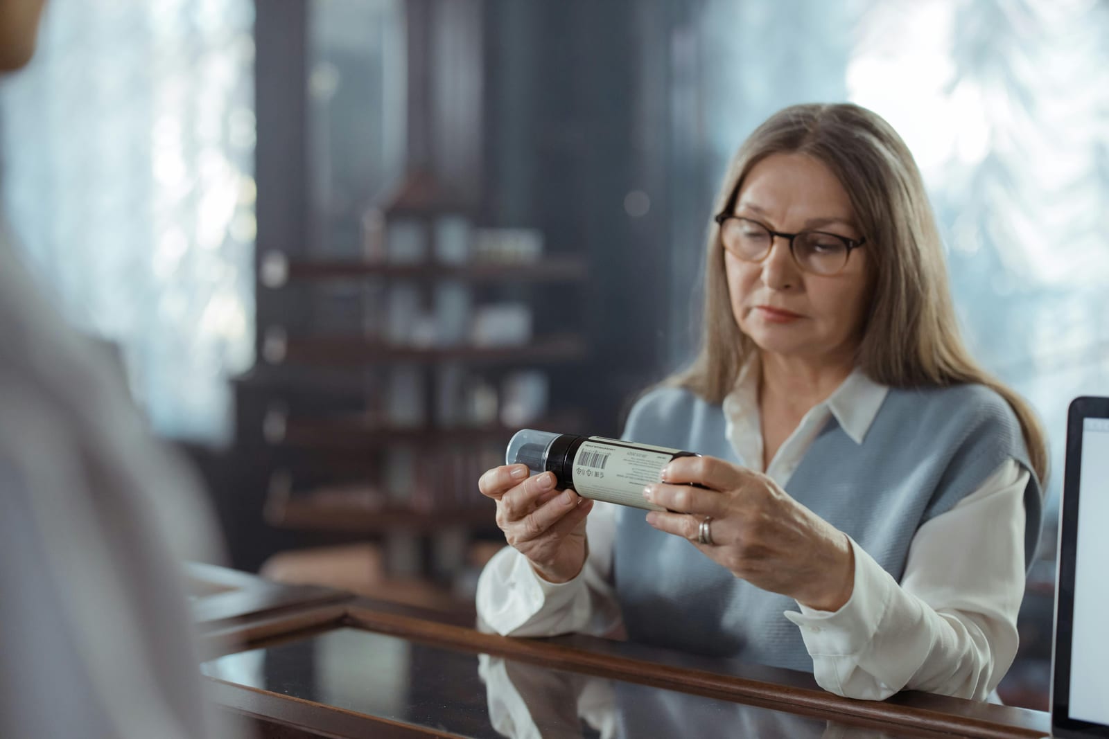 Žena si v obchodě prohlíží etiketu na lahvičce s doplňkem stravy