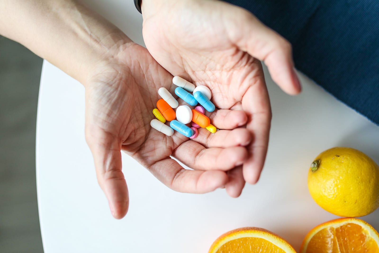 Ruka drží různobarevné tablety, kapsle a vitamíny