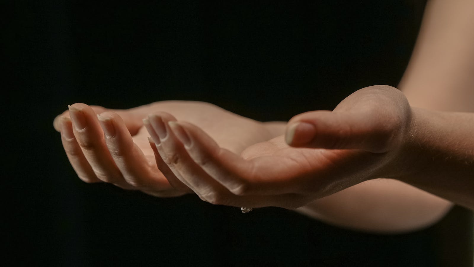 Otevřené dlaně v měkkém světle, symbol darování a péče