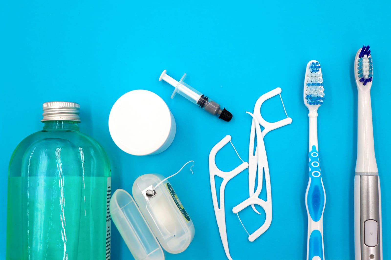 Zubní kartáčky, niť a další dentální pomůcky na bílém podkladu