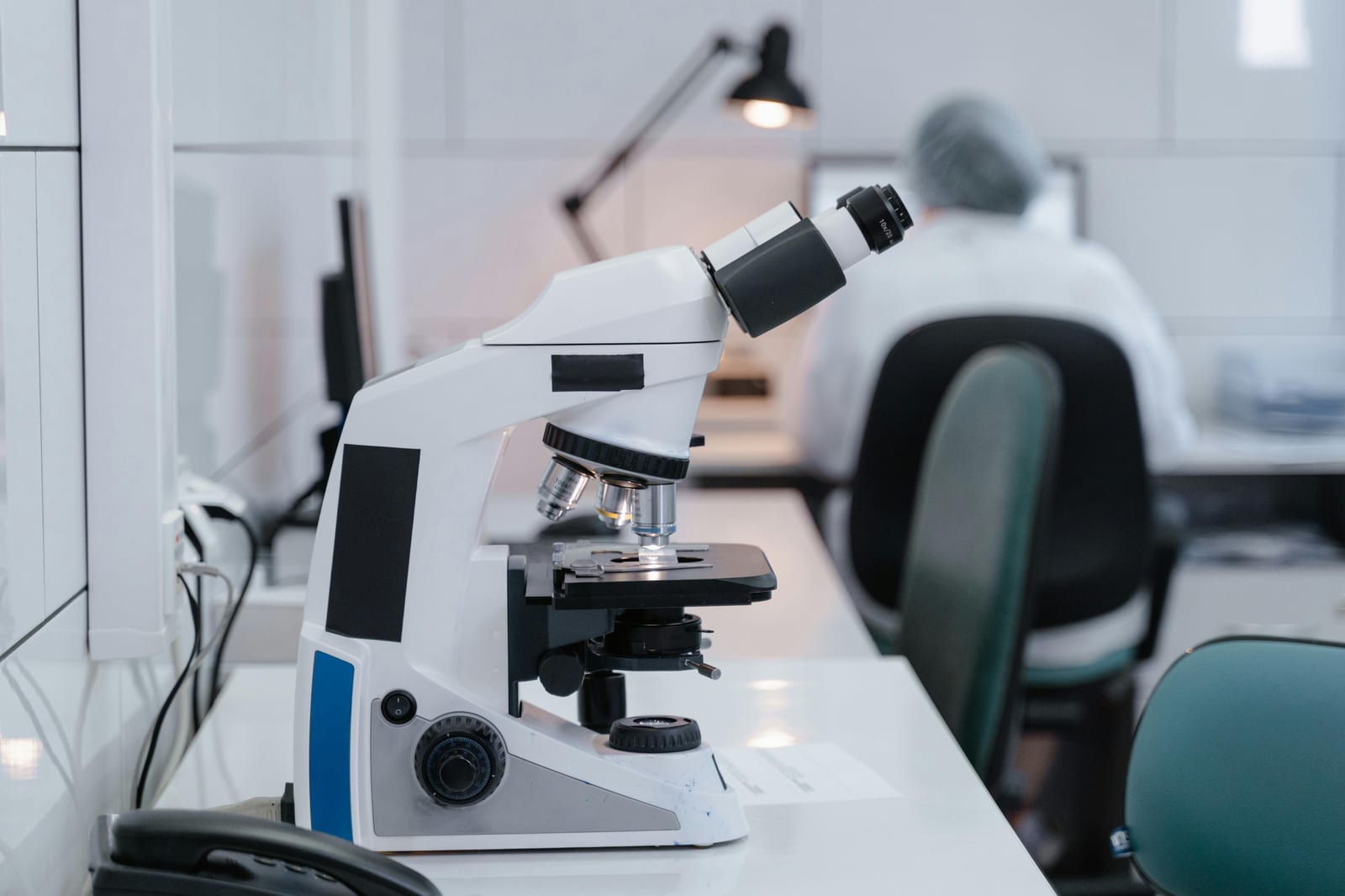 Vědec u mikroskopu v laboratoři, soustředěná práce s biologickým vzorkem