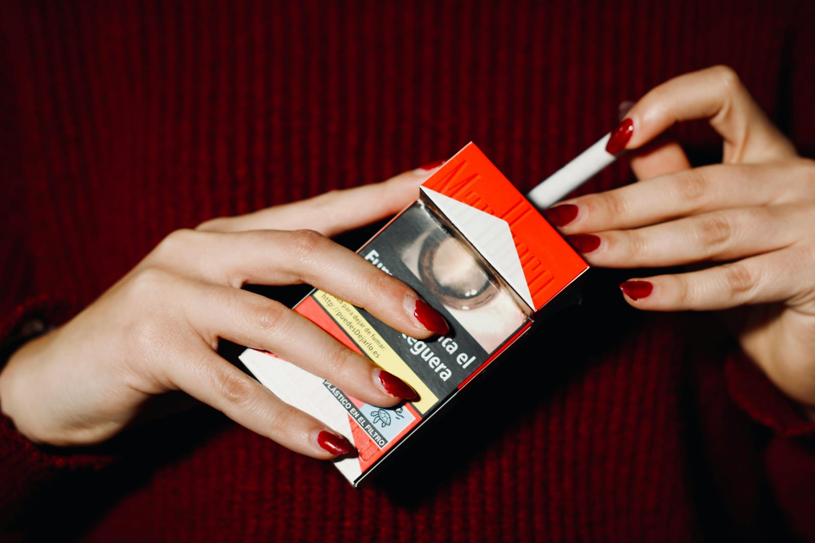 Ruce drží otevřenou krabičku cigaret s viditelným zdravotním varováním
