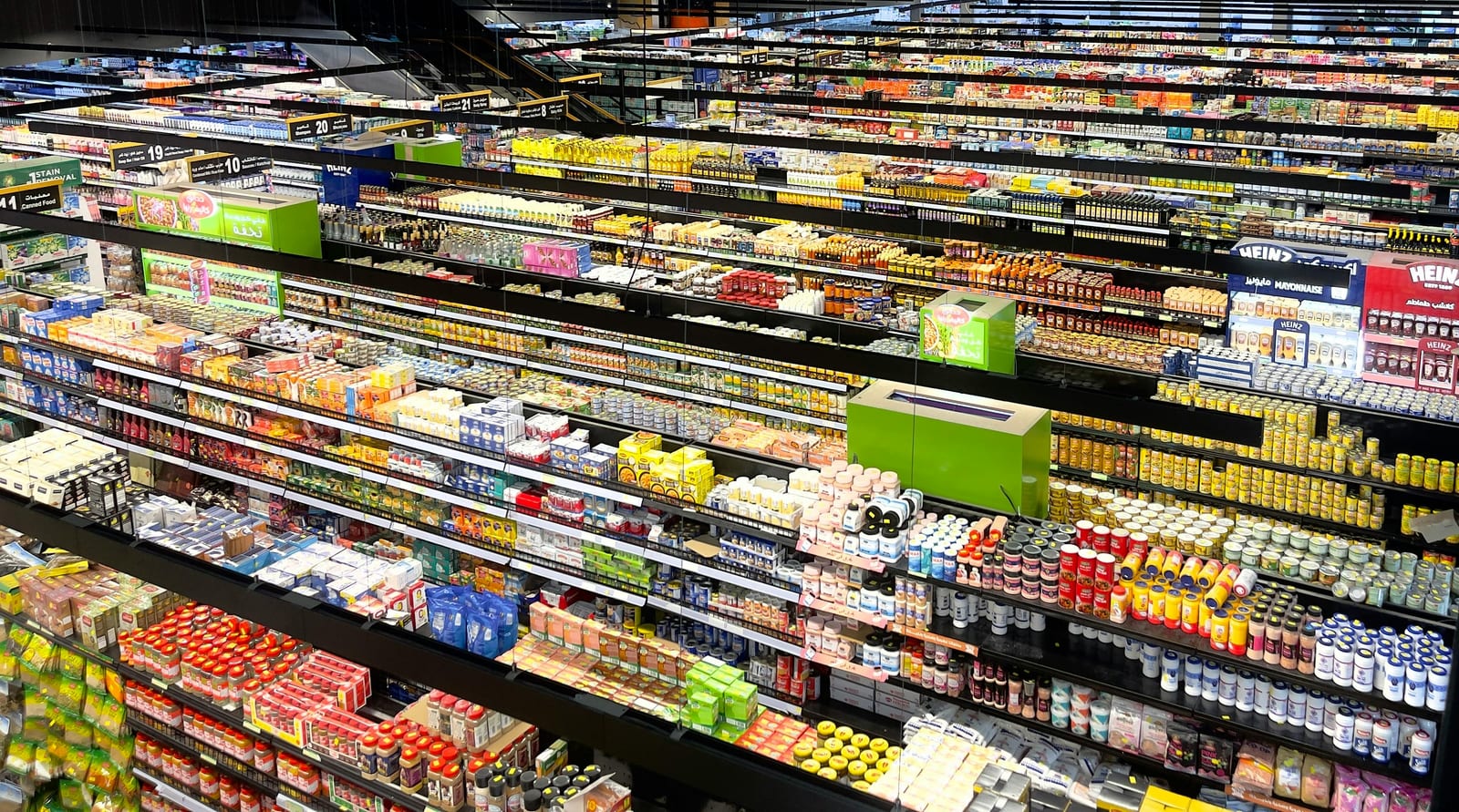 Široký pohled na regály supermarketu plné barevných obalů a zpracovaných potravin