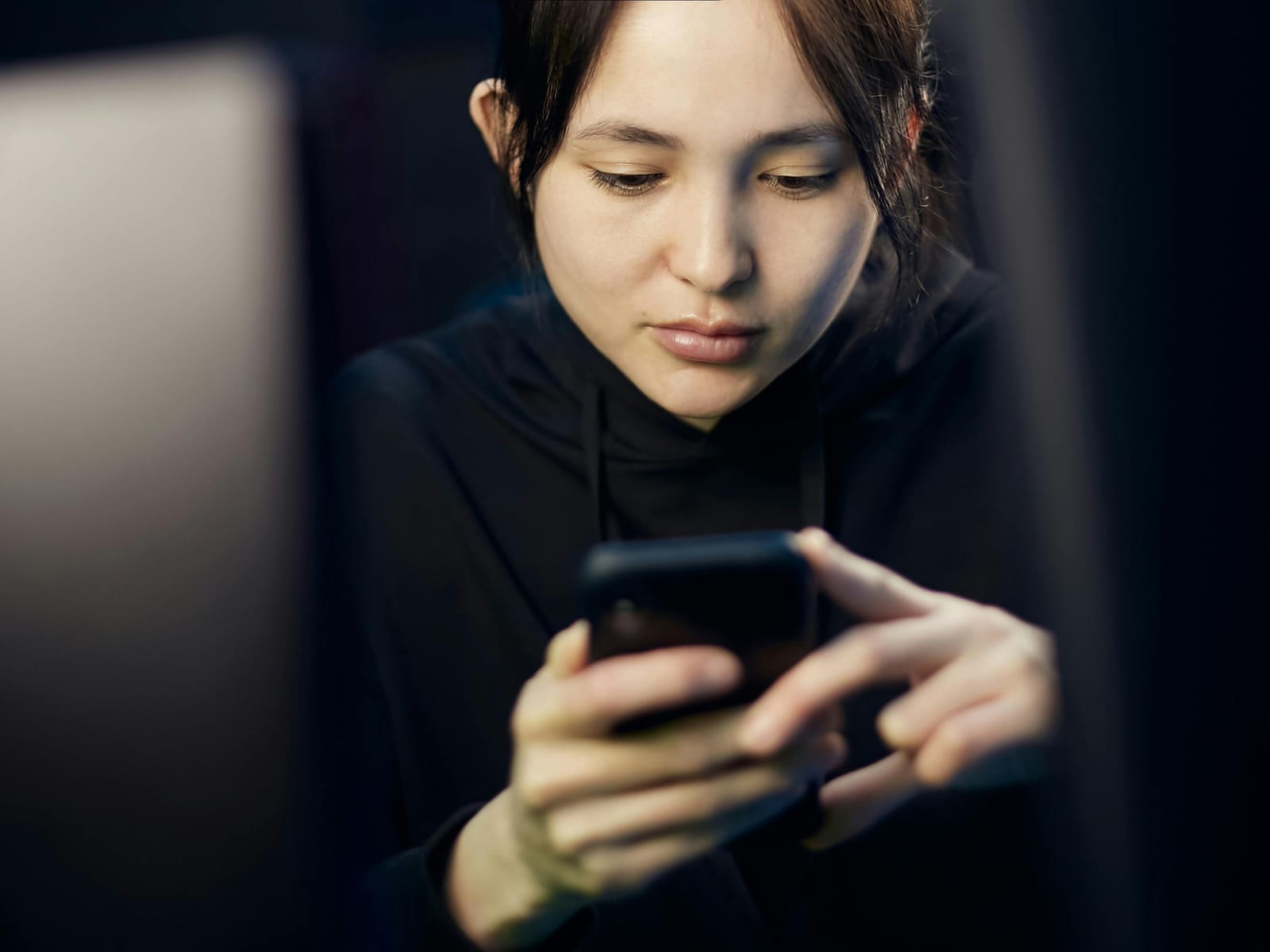 Mladá žena se zaujetím sleduje displej smartphonu