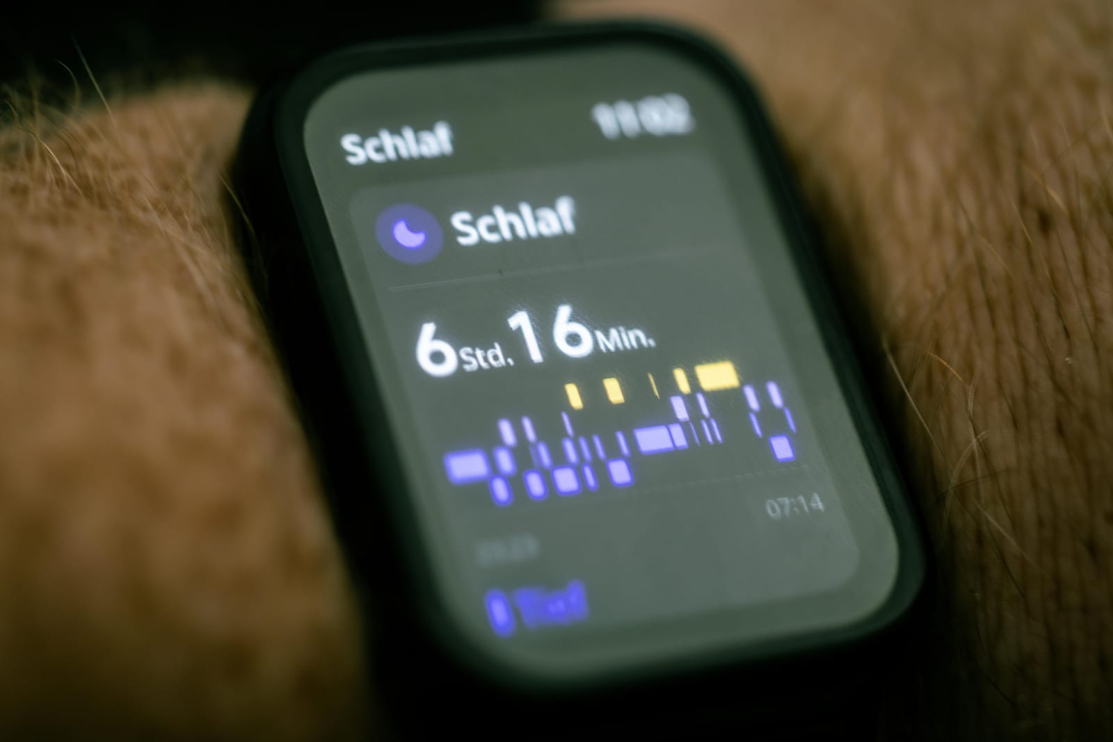Telefon s aplikací pro sledování spánku, modrý graf na nočním stolku