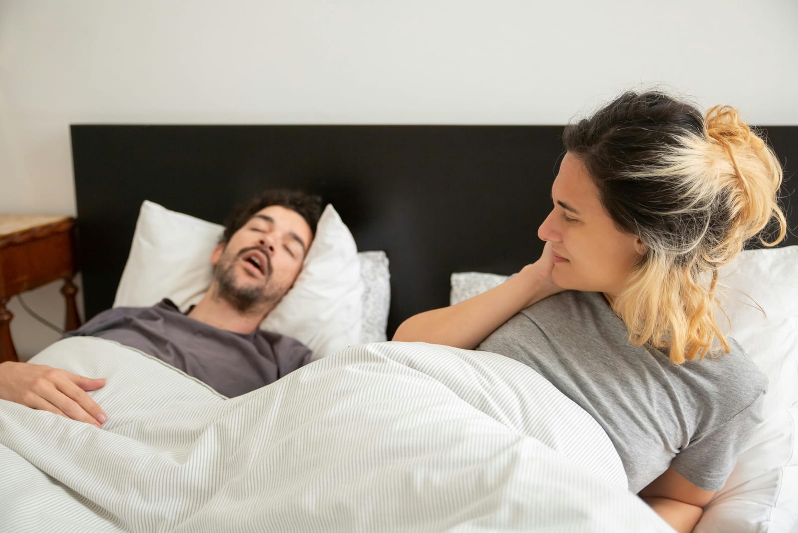 Muž tvrdě spí s otevřenými ústy, partnerka vedle něj leží vzhůru