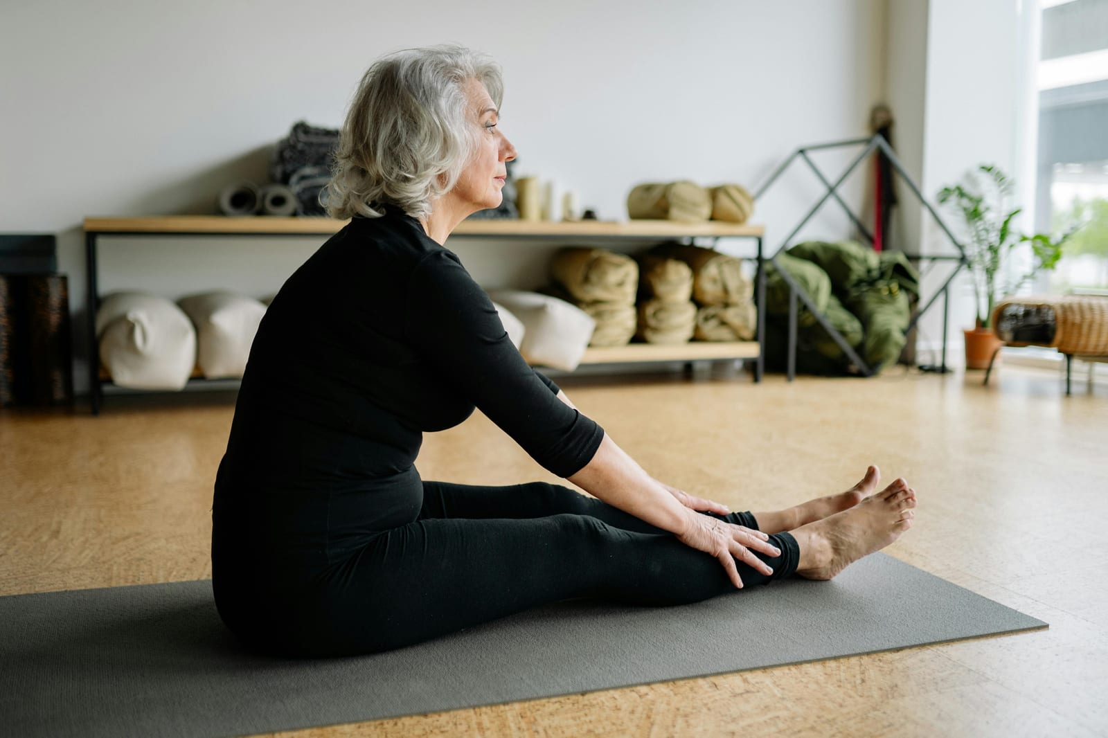 Žena ve středním věku cvičí pilates nebo strečink na podložce