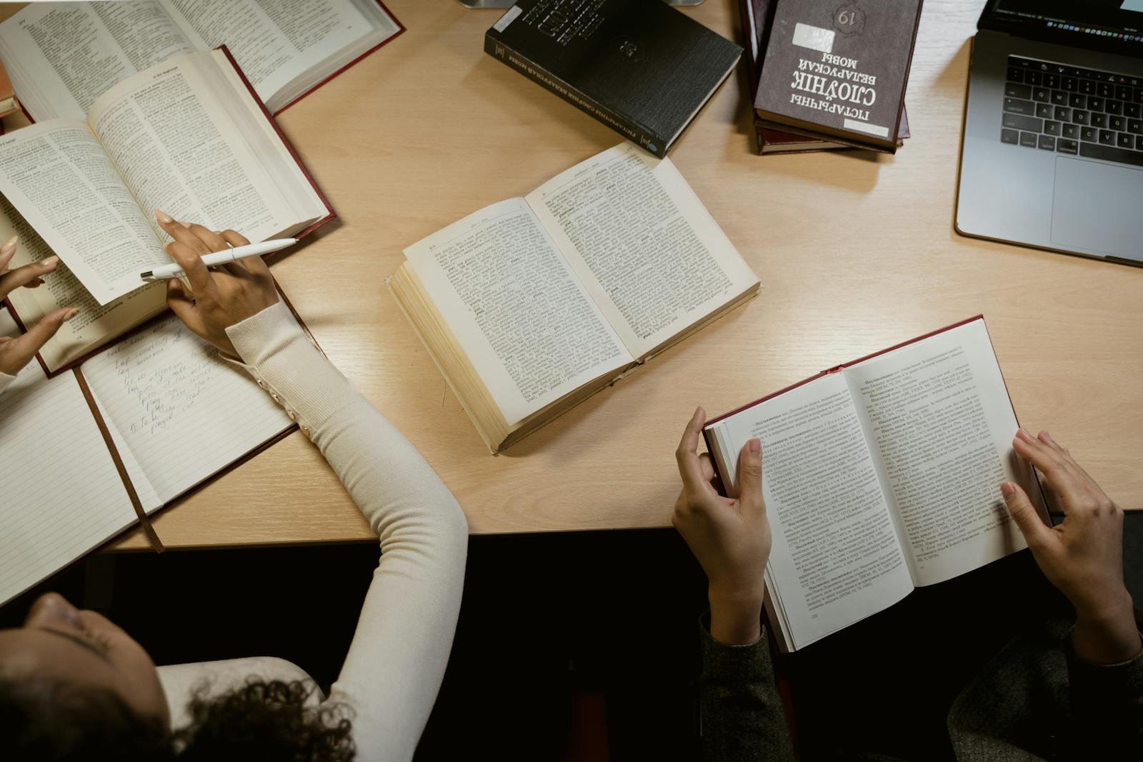 Skupina dospělých studuje společně s otevřenými knihami a notebooky