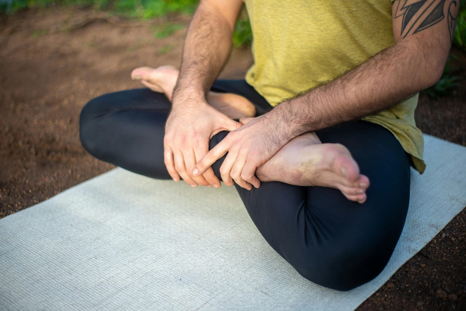 Detail nohou zkřížených do meditačního sedu na podložce