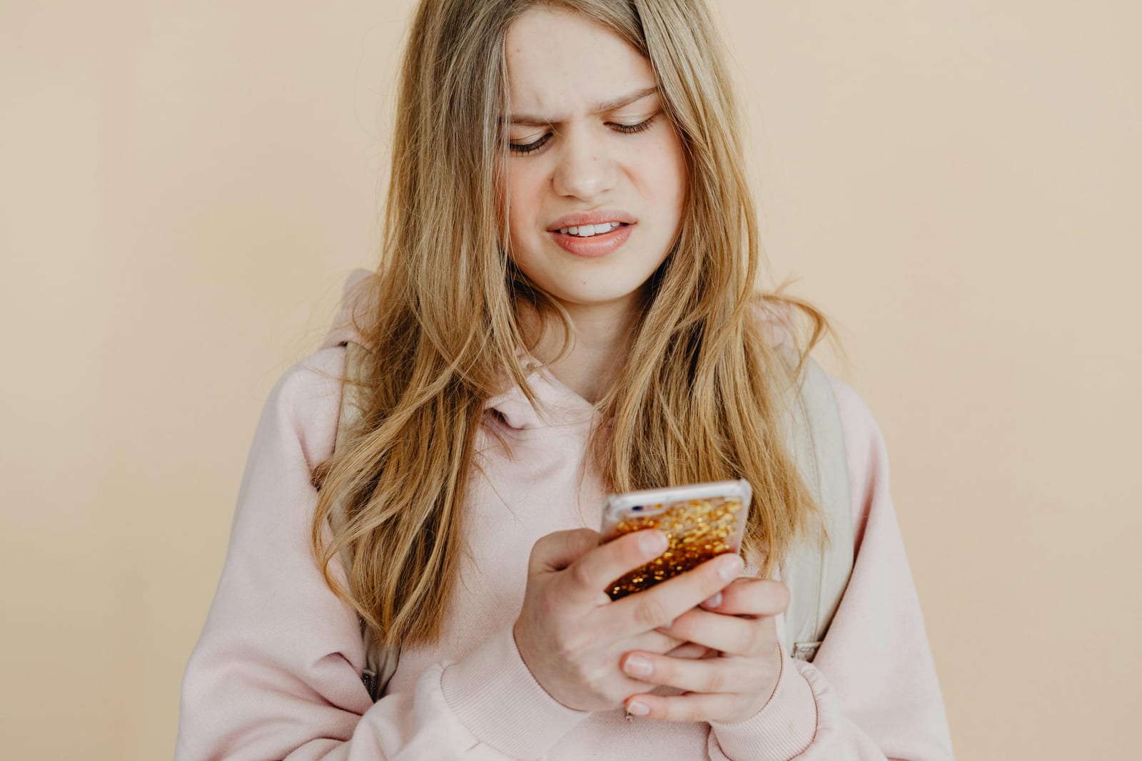 Žena se zachmuřeně dívá do telefonu
